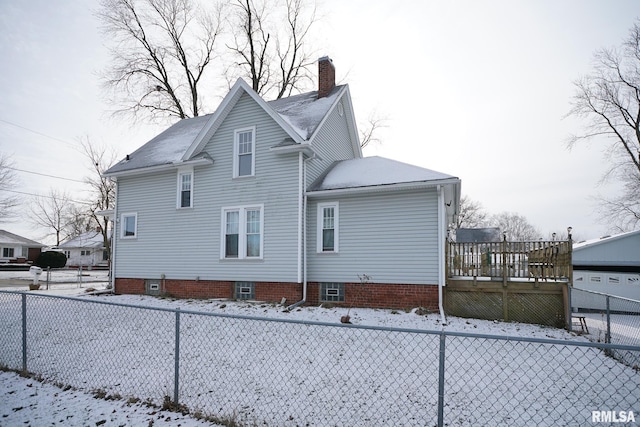 snow covered back of property featuring a deck