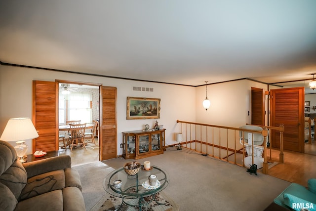 living room featuring light carpet, ceiling fan, and ornamental molding