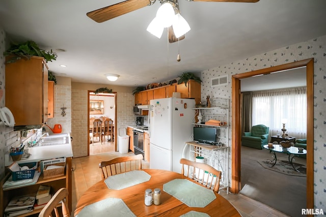 tiled dining space featuring ceiling fan and sink