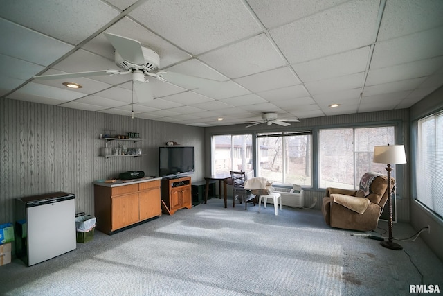 sunroom / solarium with ceiling fan, a drop ceiling, and an AC wall unit