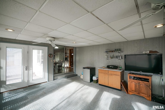 living room with ceiling fan, a drop ceiling, and carpet