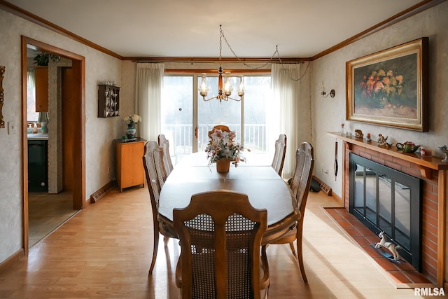 dining space with a fireplace, light hardwood / wood-style floors, a chandelier, and crown molding