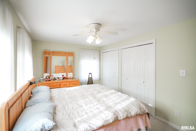 carpeted bedroom with ceiling fan and two closets