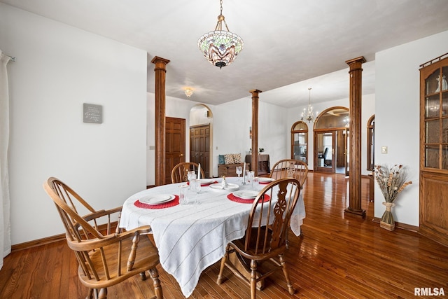 dining room with a chandelier, ornate columns, and dark wood-type flooring