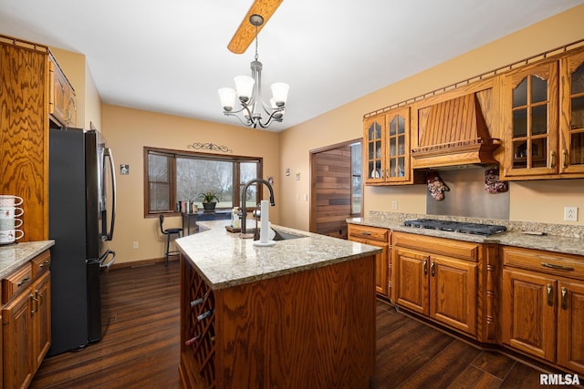 kitchen featuring light stone countertops, sink, stainless steel appliances, an island with sink, and a chandelier