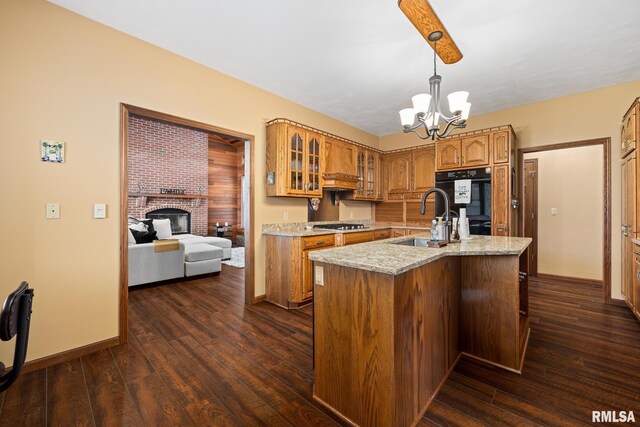 kitchen featuring custom exhaust hood, sink, light stone countertops, an island with sink, and decorative light fixtures