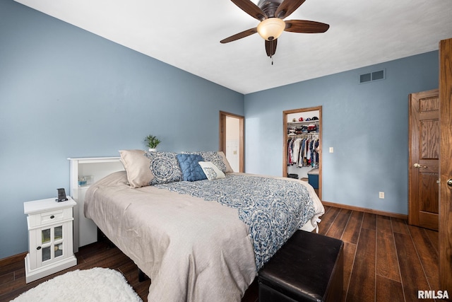 bedroom with ceiling fan, dark hardwood / wood-style flooring, a walk in closet, and a closet