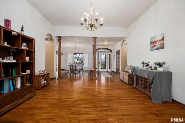 foyer featuring ornate columns, a chandelier, and hardwood / wood-style flooring