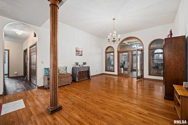 interior space with hardwood / wood-style floors, an inviting chandelier, and ornate columns