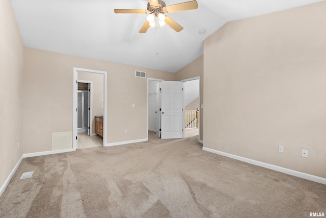 unfurnished bedroom featuring ensuite bath, ceiling fan, light colored carpet, and vaulted ceiling