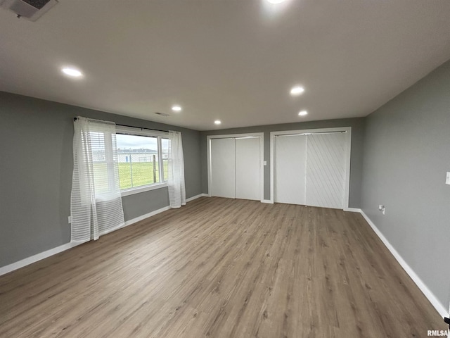 unfurnished bedroom with wood-type flooring and multiple closets