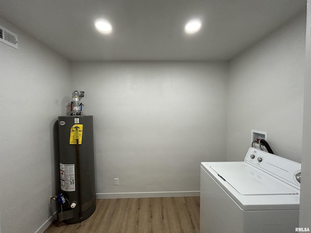 laundry room with water heater, hardwood / wood-style flooring, and washer / dryer