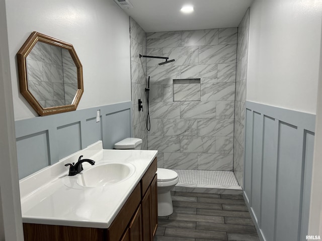 bathroom featuring a tile shower, vanity, and toilet