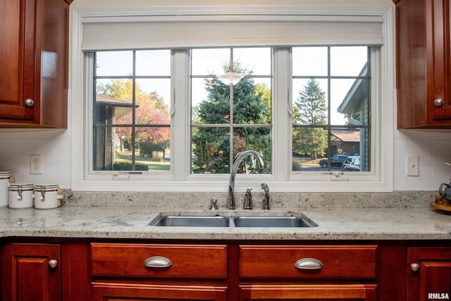 interior details with decorative backsplash, light stone countertops, and sink