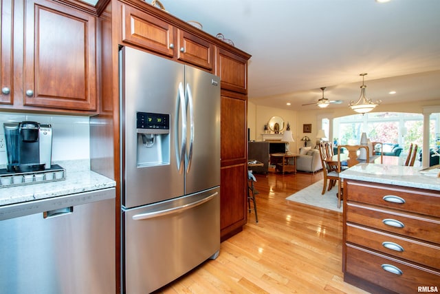 kitchen featuring light stone countertops, ceiling fan, tasteful backsplash, appliances with stainless steel finishes, and light wood-type flooring