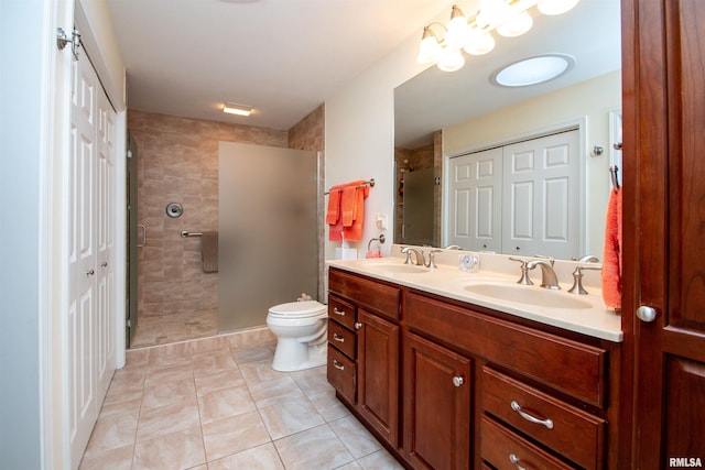 bathroom with toilet, a tile shower, vanity, and tile patterned floors