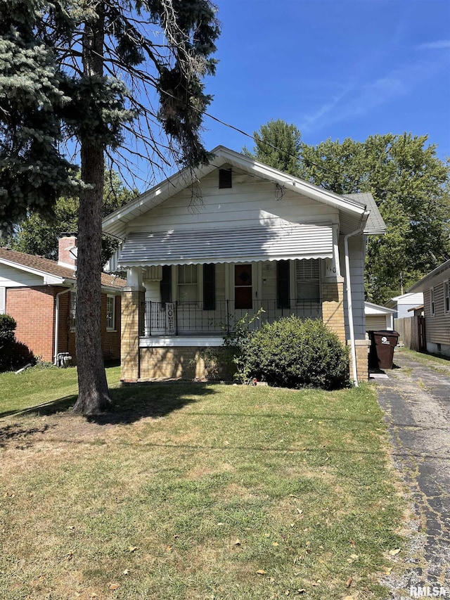 bungalow with covered porch and a front lawn