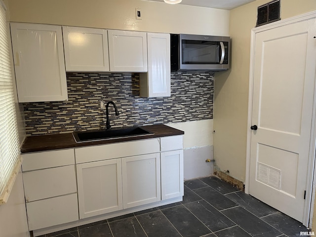 kitchen featuring white cabinetry, sink, and tasteful backsplash