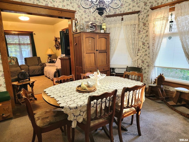 carpeted dining area with a chandelier