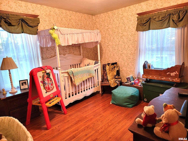 bedroom featuring a nursery area and hardwood / wood-style flooring