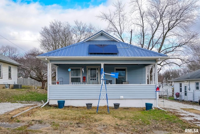 bungalow with central air condition unit, a porch, and solar panels