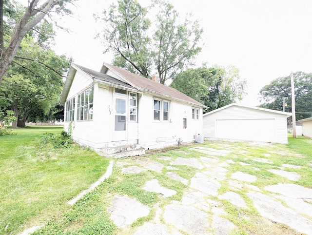 exterior space featuring a garage, an outdoor structure, and a front lawn