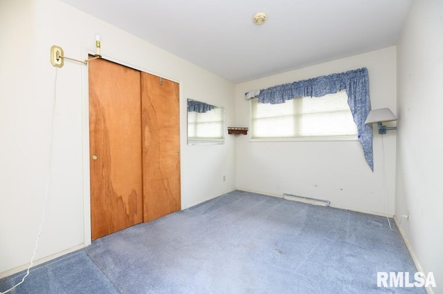 unfurnished bedroom featuring carpet floors, a baseboard radiator, and a closet