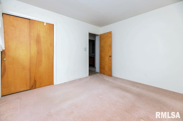 unfurnished bedroom featuring light carpet and a closet