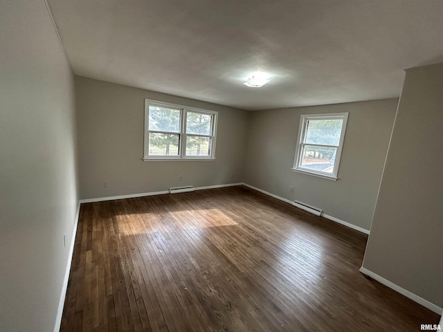 unfurnished room with baseboard heating, a wealth of natural light, and dark hardwood / wood-style floors