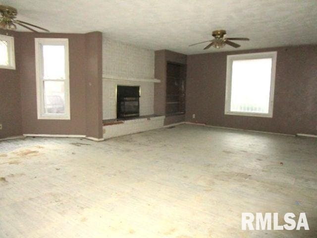 unfurnished living room with ceiling fan and a fireplace