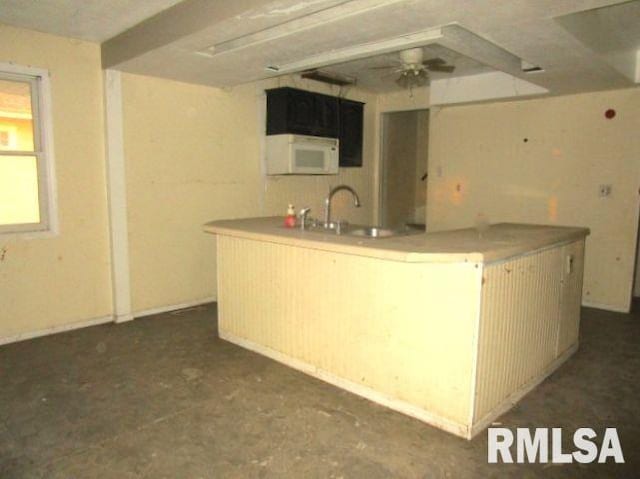 534 S Main St, Canton, IL 61520 - kitchen featuring a sink, white microwave, a center island with sink, and light countertops