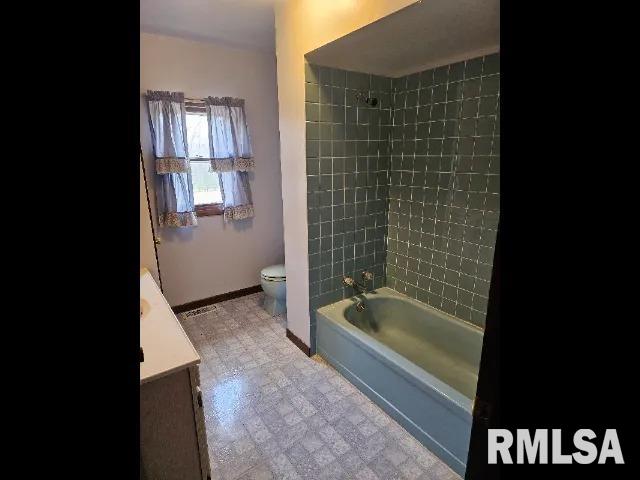 full bathroom with toilet, vanity, and tiled shower / bath combo