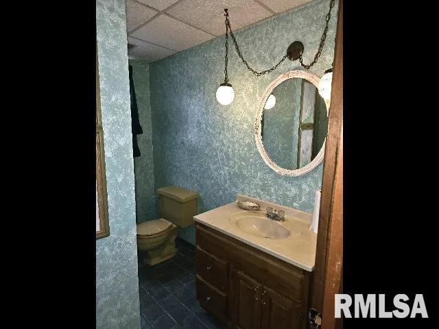 bathroom with tile patterned flooring, vanity, a paneled ceiling, and toilet