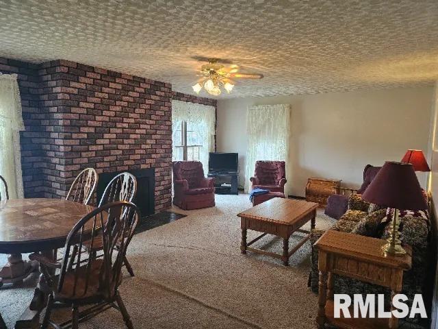 carpeted living room with ceiling fan and a textured ceiling