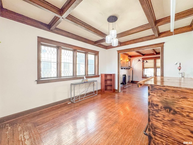 unfurnished living room with coffered ceiling, wood-type flooring, beamed ceiling, and a brick fireplace