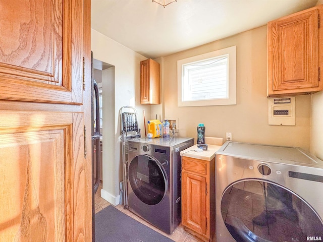 clothes washing area with cabinets, light tile patterned floors, and washer and clothes dryer