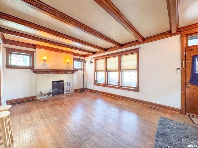 unfurnished living room featuring beam ceiling, wood-type flooring, and a brick fireplace