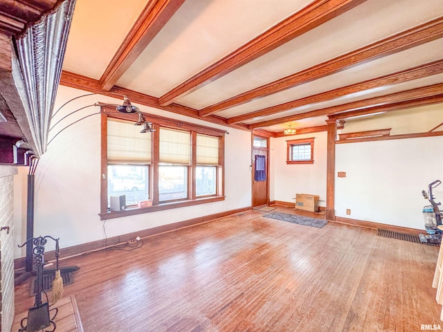 unfurnished living room with beamed ceiling, hardwood / wood-style flooring, and a brick fireplace