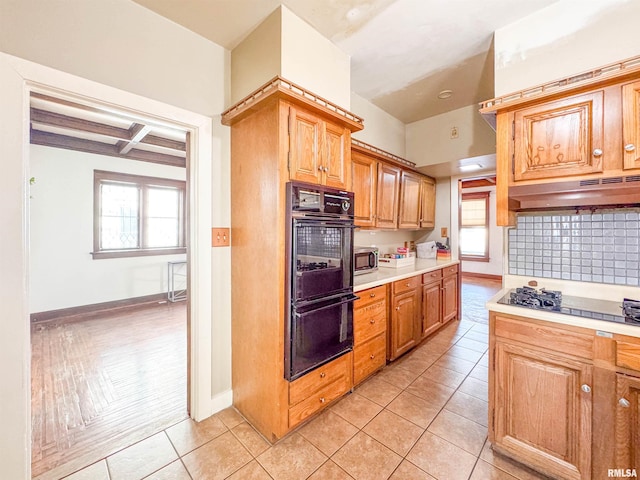 kitchen featuring double oven, light tile patterned floors, beamed ceiling, and coffered ceiling