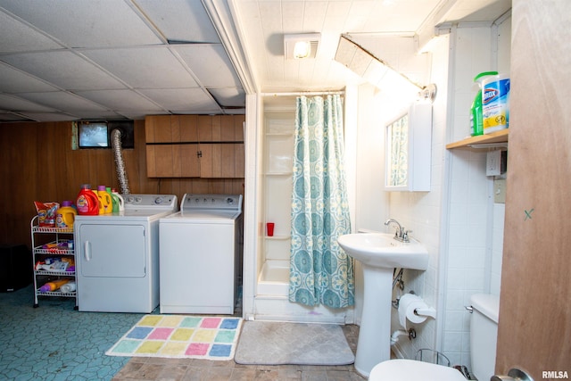 laundry area with washing machine and dryer, wood walls, and sink