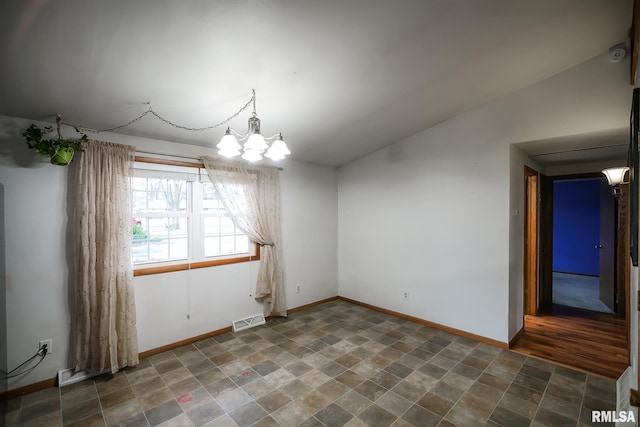 empty room featuring a chandelier and lofted ceiling