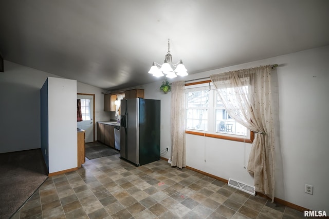 kitchen featuring stainless steel appliances, vaulted ceiling, and an inviting chandelier