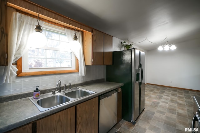 kitchen with sink, stainless steel appliances, a notable chandelier, decorative light fixtures, and decorative backsplash