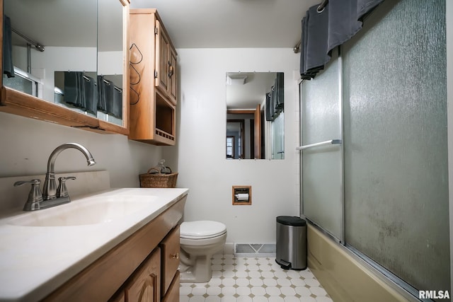 full bathroom with combined bath / shower with glass door, vanity, and toilet