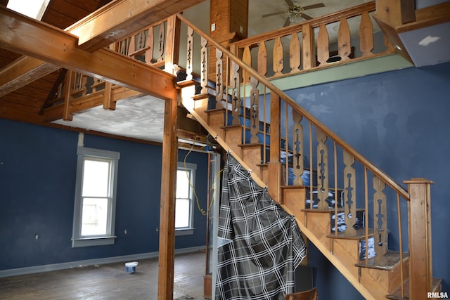 stairway featuring wood-type flooring, ceiling fan, and beam ceiling