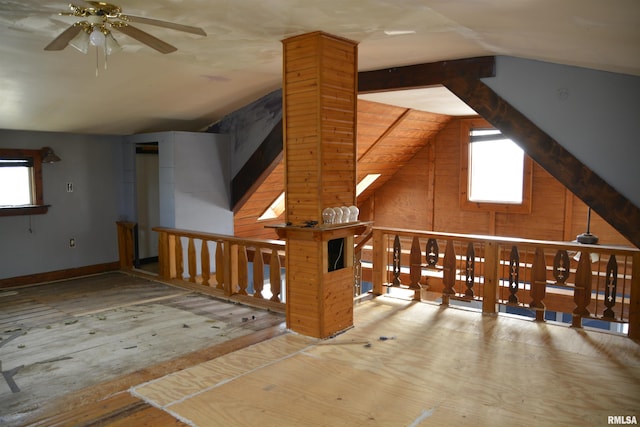 additional living space featuring ceiling fan, lofted ceiling, and wooden walls