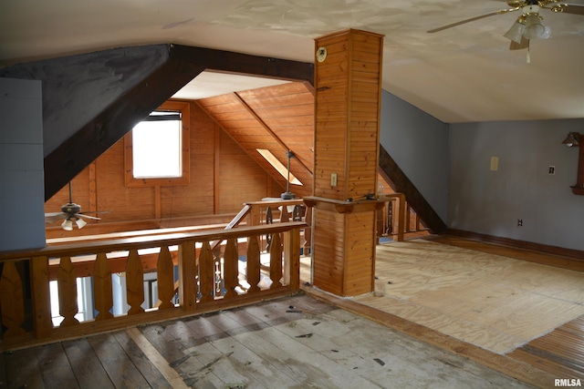 bonus room featuring wood-type flooring, lofted ceiling with skylight, ceiling fan, and wood walls