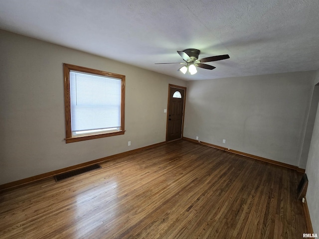 spare room featuring ceiling fan, dark wood-type flooring, and a textured ceiling