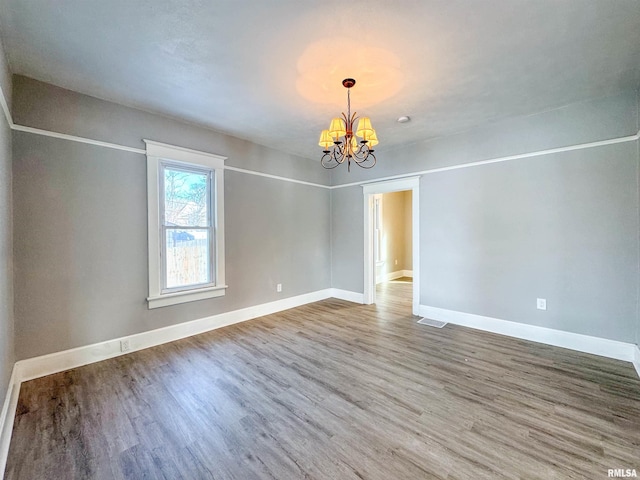 unfurnished room featuring hardwood / wood-style floors and an inviting chandelier