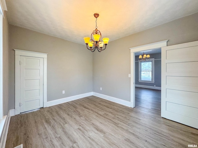 unfurnished room featuring a chandelier and wood-type flooring